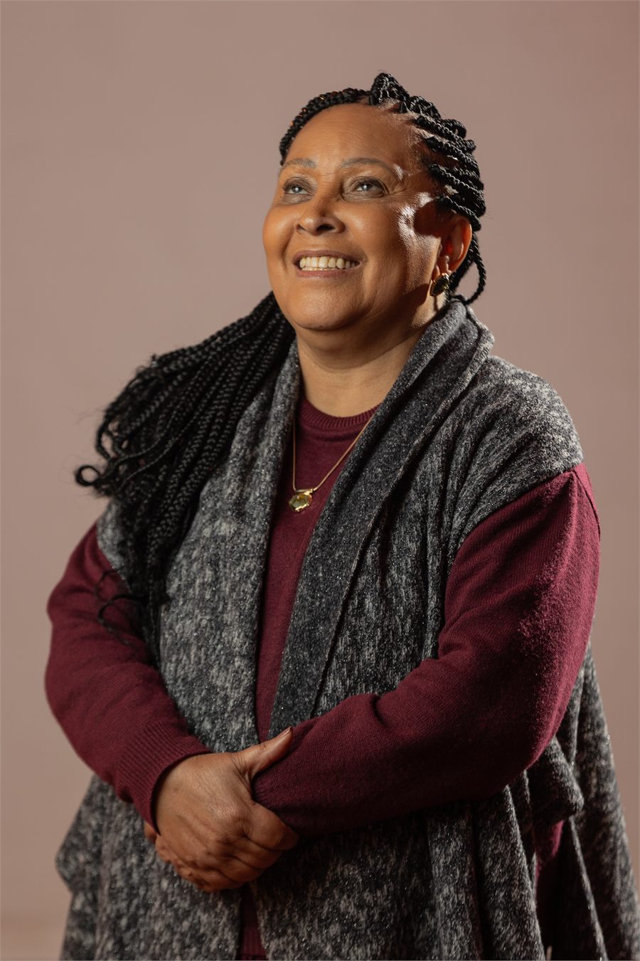 Retrato de Carmen Silva sorrindo, olhando para cima, de tranças e xale cinza.